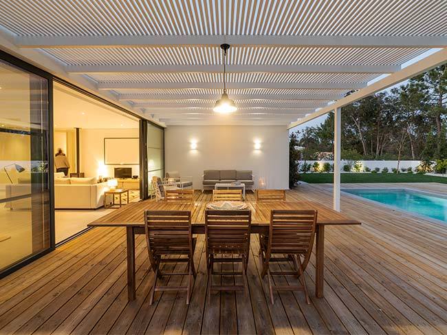 An outdoor entertainment area with a large table and chairs and a pool