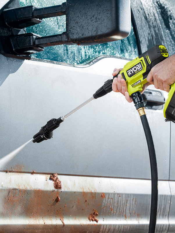 A Ryobi pressure washer used to clean a dirty, grey car