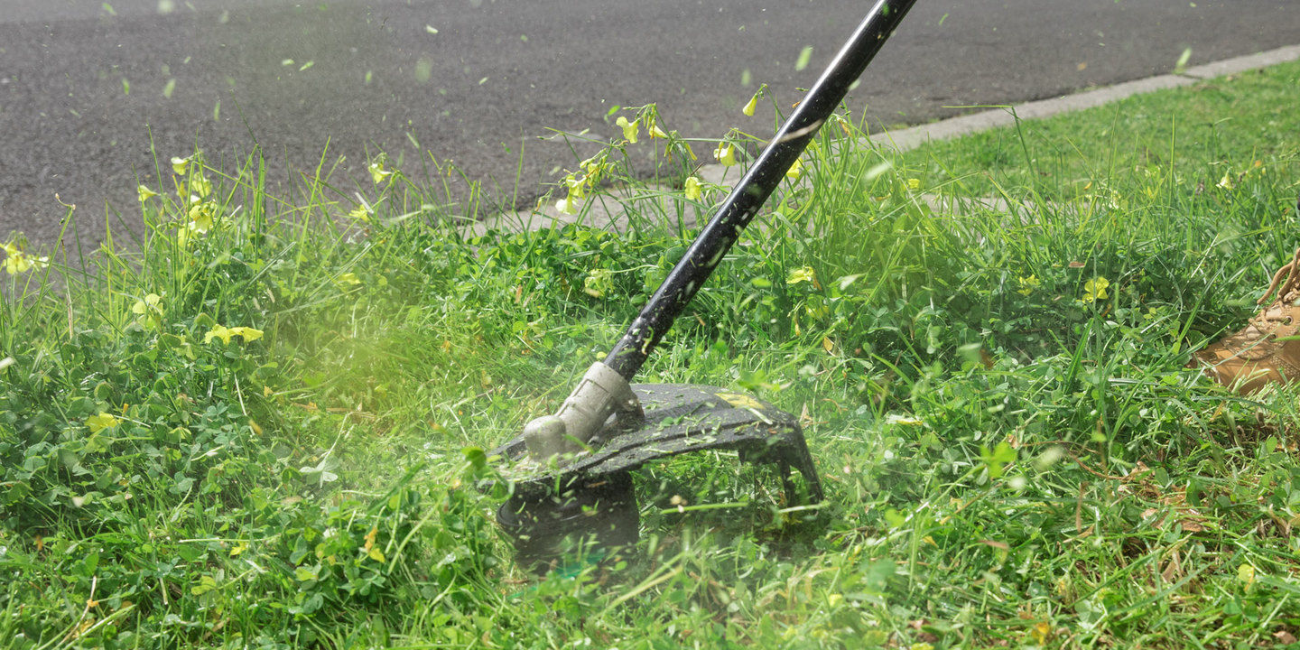 A Ryobi line trimmer cutting weeds and long grass