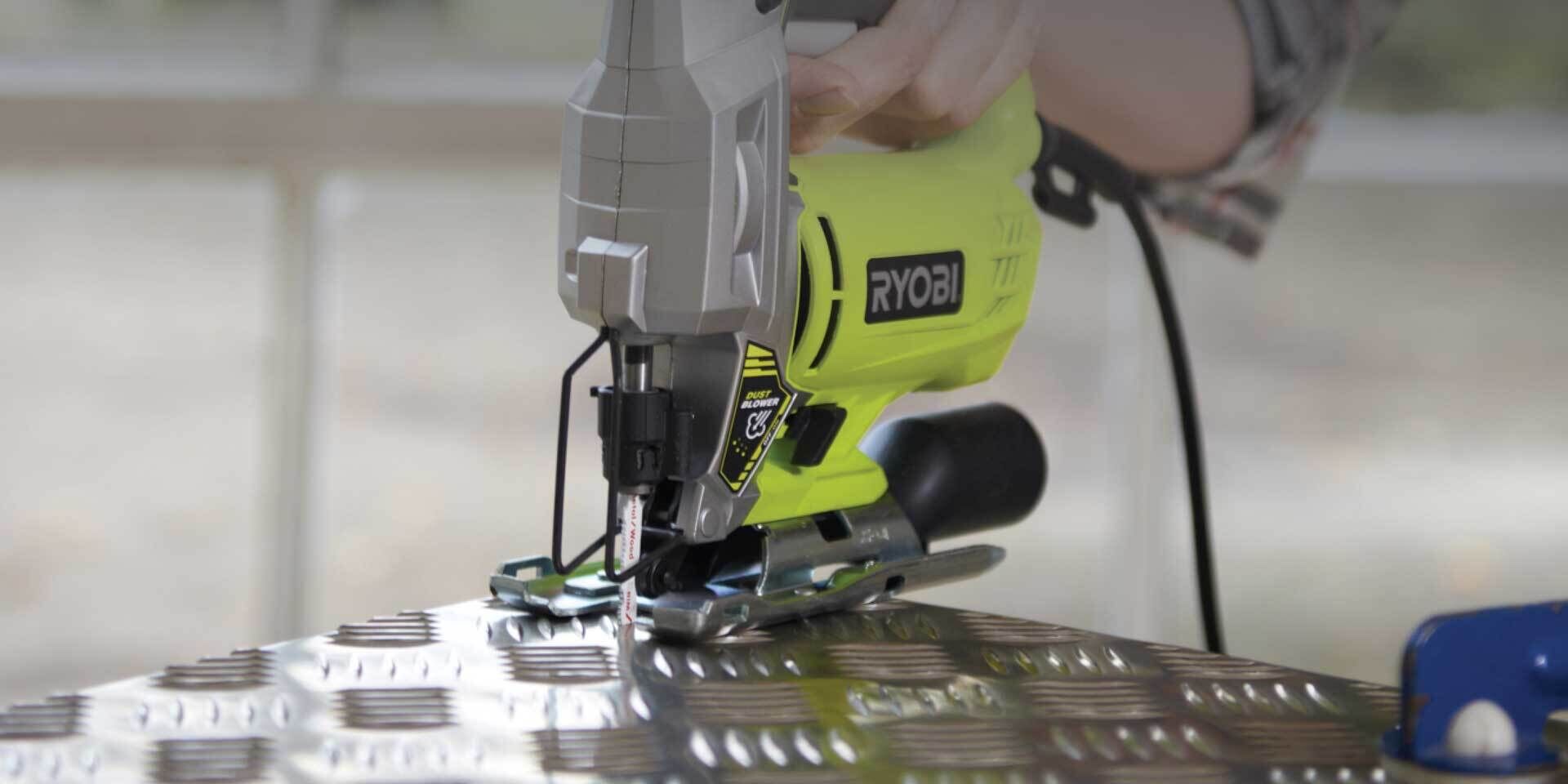 A Ryobi jigsaw being used to cut through metal