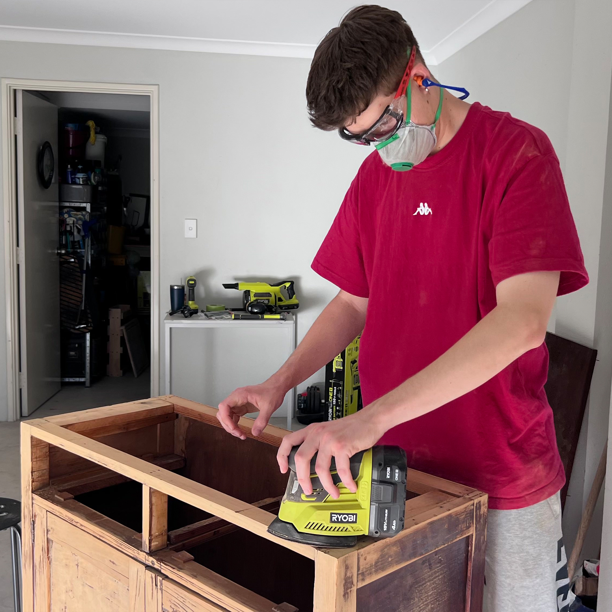 Using a RYOBI Sander to strip back old timber cabinet