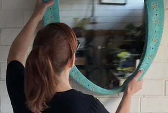 Natasha hangs her DIY ornate mirror frame on a white brick wall