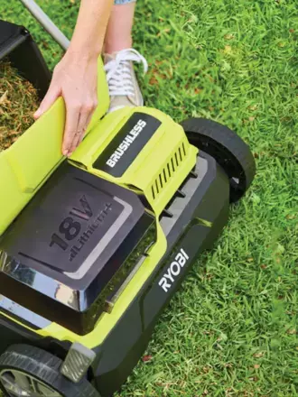 Hand emptying a full grass catcher on a RYOBI scarifier tool