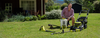 Jason Hodges kneels on the grass with a range of RYOBI garden products